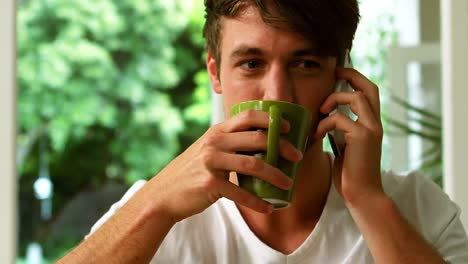 Handsome-man-using-mobile-phone-in-the-kitchen