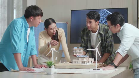 grupo de ingenieros asiáticos teniendo una reunión sobre el modelo de casas pequeñas con panel solar en la oficina