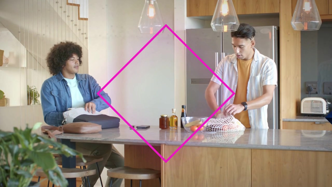 Due uomini che frugono in una borsa tirando fuori del cibo, l'uomo a destra che impacchetta frutta mentre una gemma magenta oscura