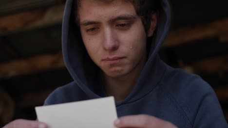 A-young-teenager-sits-in-a-garage-looking-at-a-picture-of-his-dad