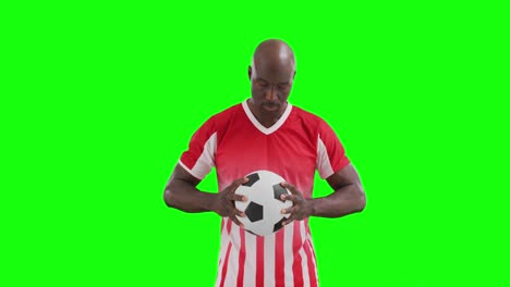 Video-of-african-american-male-soccer-player-holding-ball-on-green-screen-background