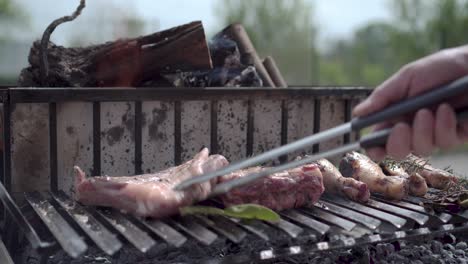 Turning-rib-rack-with-rosemary-on-fire-barbecue-grill-close-up