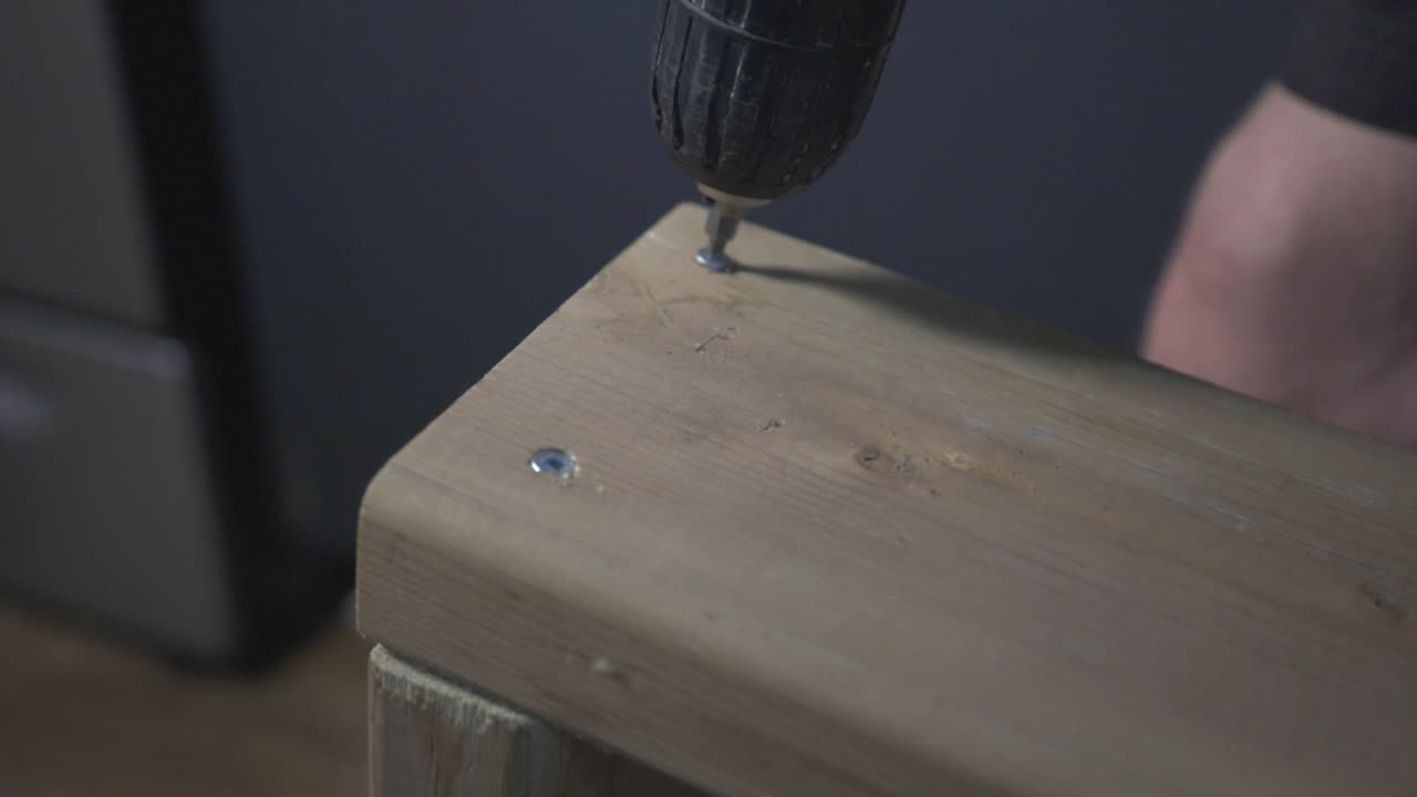 A Carpenter Screwing A Wooden Board By An Electric Drill Driver. -close up shot