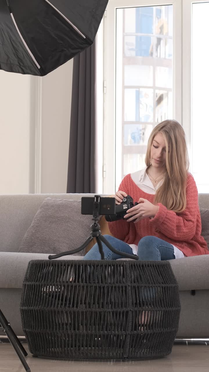 Young woman talking on mobile camera, explaining a photo camera. Content creator concept