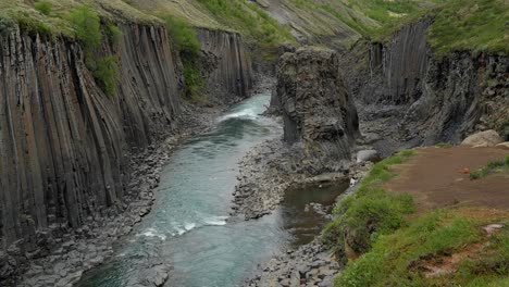 stuðlagil basalt formations cradle a tranquil blue river's flow