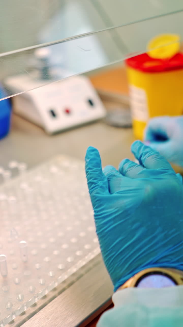 Laboratory assistant working with vials in clinic. Medical worker drops liquid into test tubes from small plastic jar. Vertical video