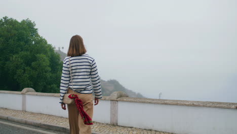 girl walking city bridge rear view vertical. lonely tourist travel explore town