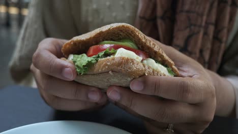 cerca de las manos de una mujer sosteniendo un sándwich fresco