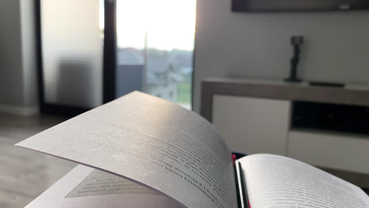 libro abierto sobre el fondo de una ventana brillante, una gran superficie de vidrio y rayos de sol que caen - cámara lenta