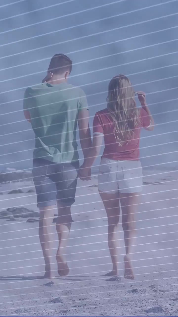 Vertical video: Pair walking sand holding hands leaving prints sun making man shielding for travel