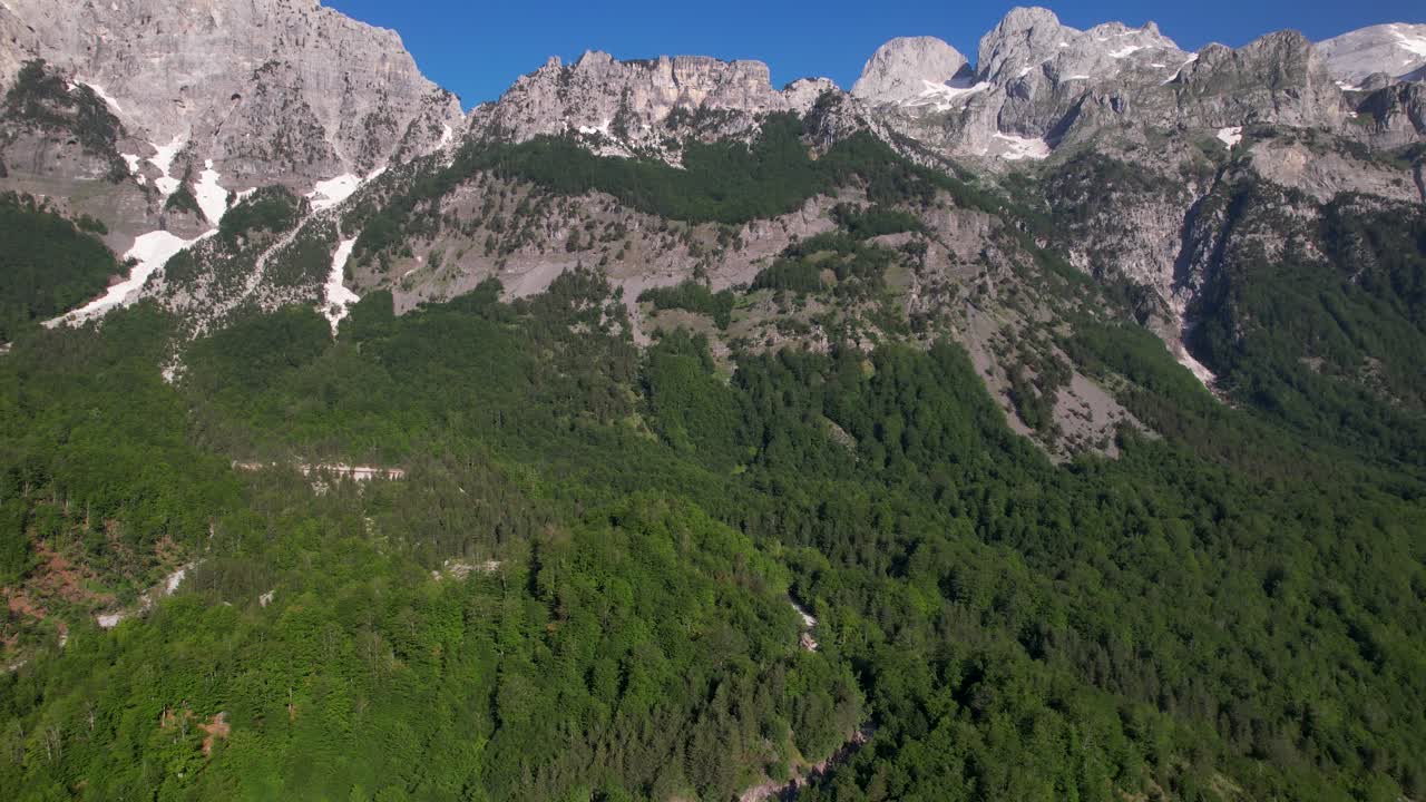 montañas alpinas en albania con rocas altas cubiertas de nieve y laderas de bosques verdes
