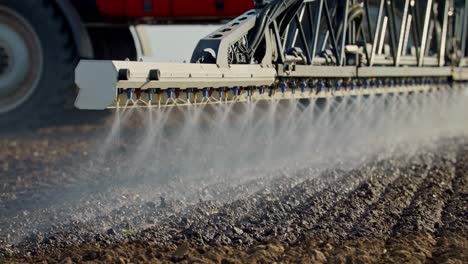 primo piano di un agricoltore che spruzza terreno su una campagna agricola da un macchinario rosso