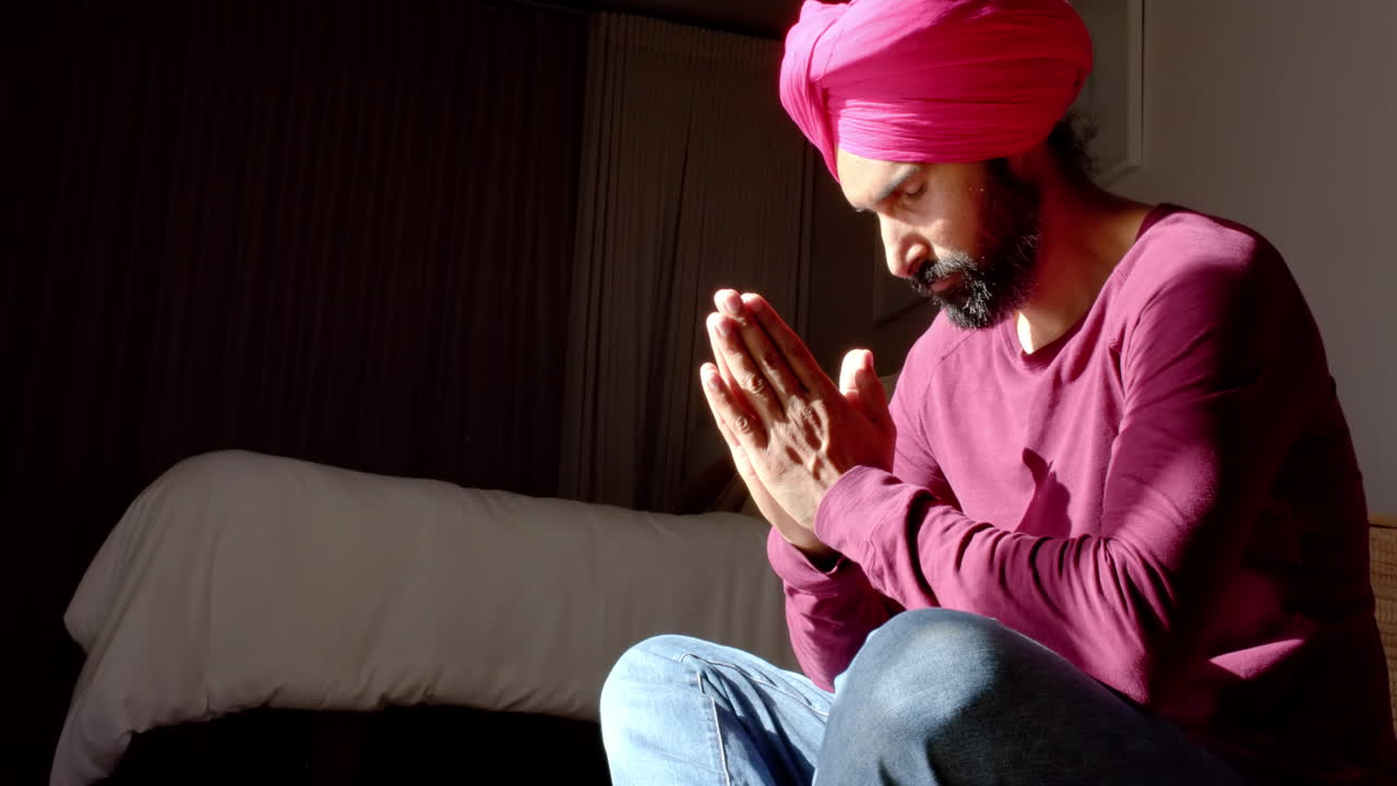 Meditating at home, man in pink turban and red shirt focusing inward