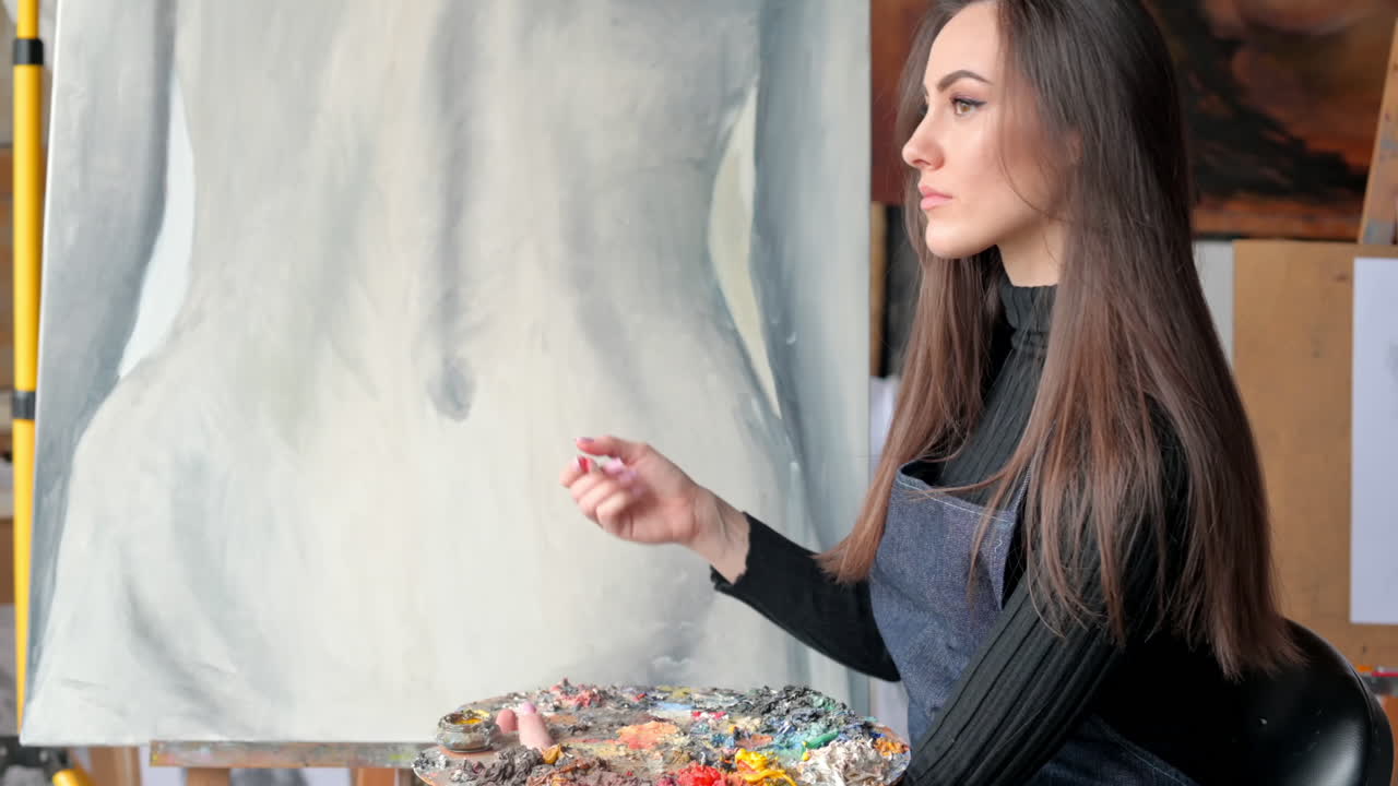Woman painting a female body on a canvas at an art gallery workshop