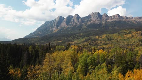 astounding-dolly-backwards-zoom-shot-of-Mount-Robson-Provincial-Park-in-the-autumn-on-a-mix-of-sun-and-clouds-day-with-mountains-in-the-background-and-colourful-trees-in-yellow-and-green