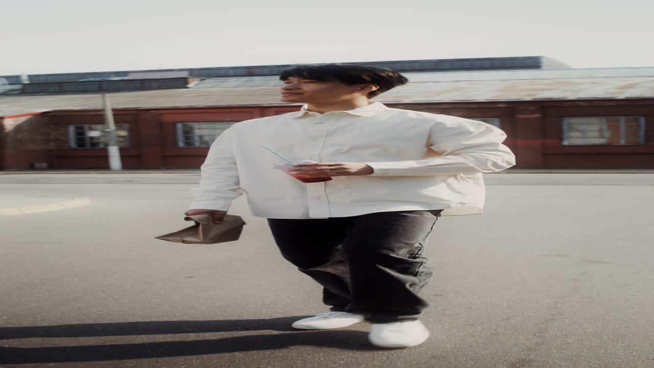 hombre caminando por la calle de la ciudad con bebida y comida