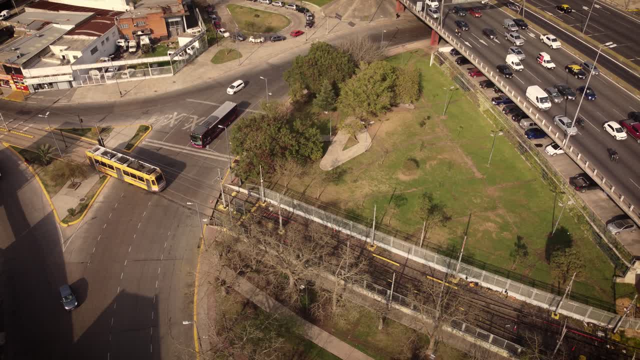 una toma aérea dinámica de un tranvía de pasajeros amarillo que cruza la carretera hacia la rotonda que llega a la terminal del metro
