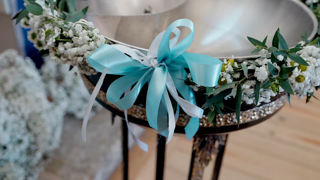 close up of baptism font with white flowers and blue ribbon in elegant indoor setting
