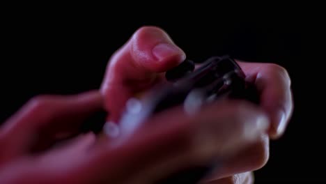 playing video games in a darkened room with a black background close up on a controller joystick playing slowly soft focus
