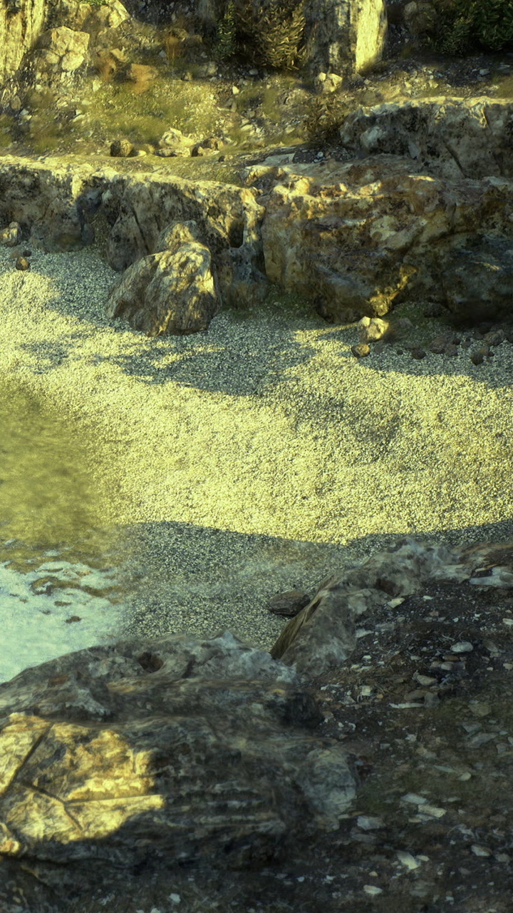 Rocky shore with pebbles and water near the landscape in sunlight