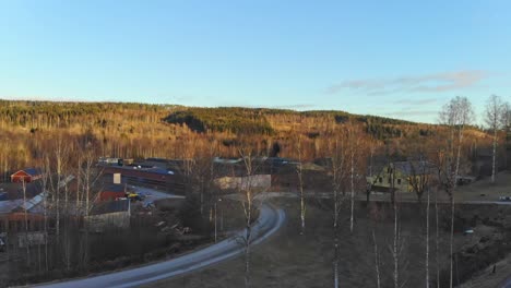 Drone-rising-over-trees-with-a-view-over-industry-building-in-Bongbro,-Sweden