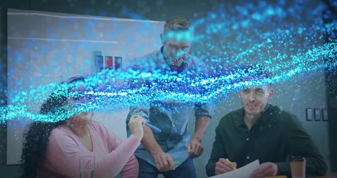 Kvinde peger på skitse, hvilket igangsætter en blå partikelanimation, mens teamet markerer papir i et designmøde.