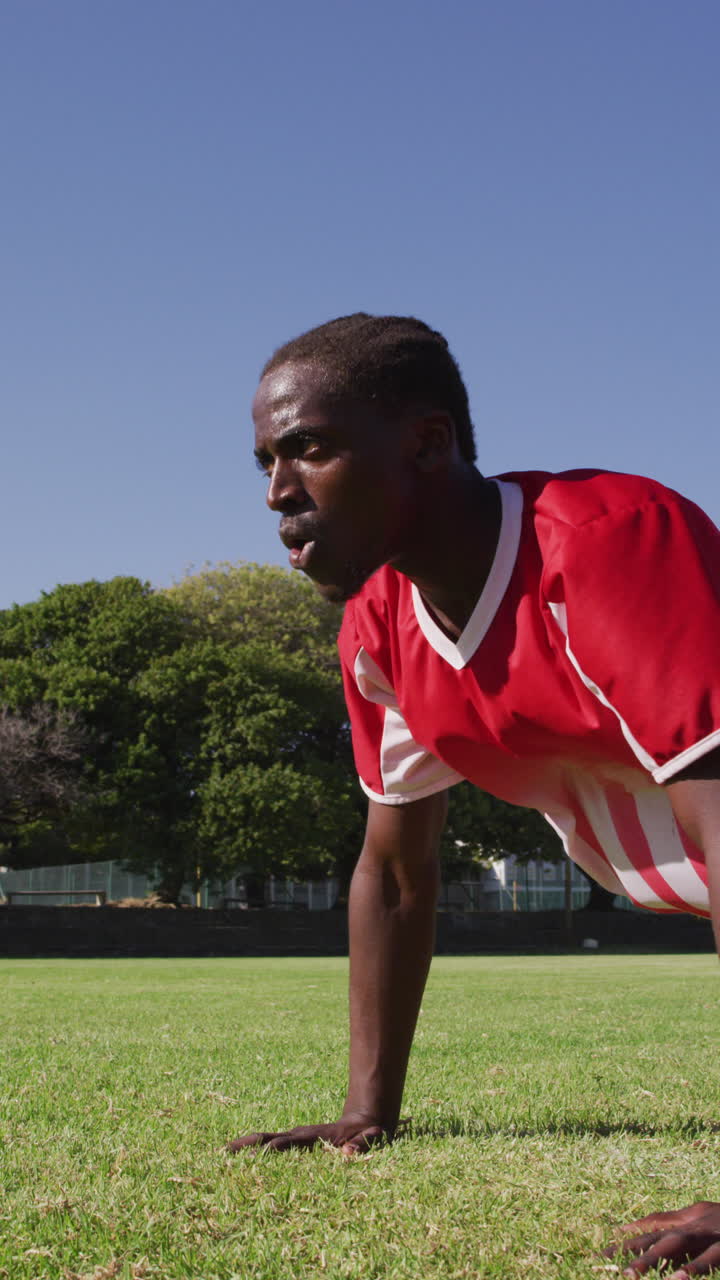 Video verticale di un giocatore di football afroamericano che fa flessioni sul campo