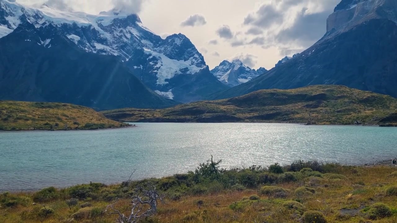 Vista tranquilla del Lago Nordenskjöld nel Parco Nazionale Torres del Paine, Patagonia, circondato da cime andine innevate sotto un cielo nuvoloso, che cattura la natura incontaminata e paesaggi iconici per l'escursionismo.