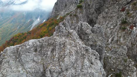 Gigantic-rock-in-the-top-of-the-Alps-in-Albanian-landscape-surrounded-by-colorful-forest-in-Autumn