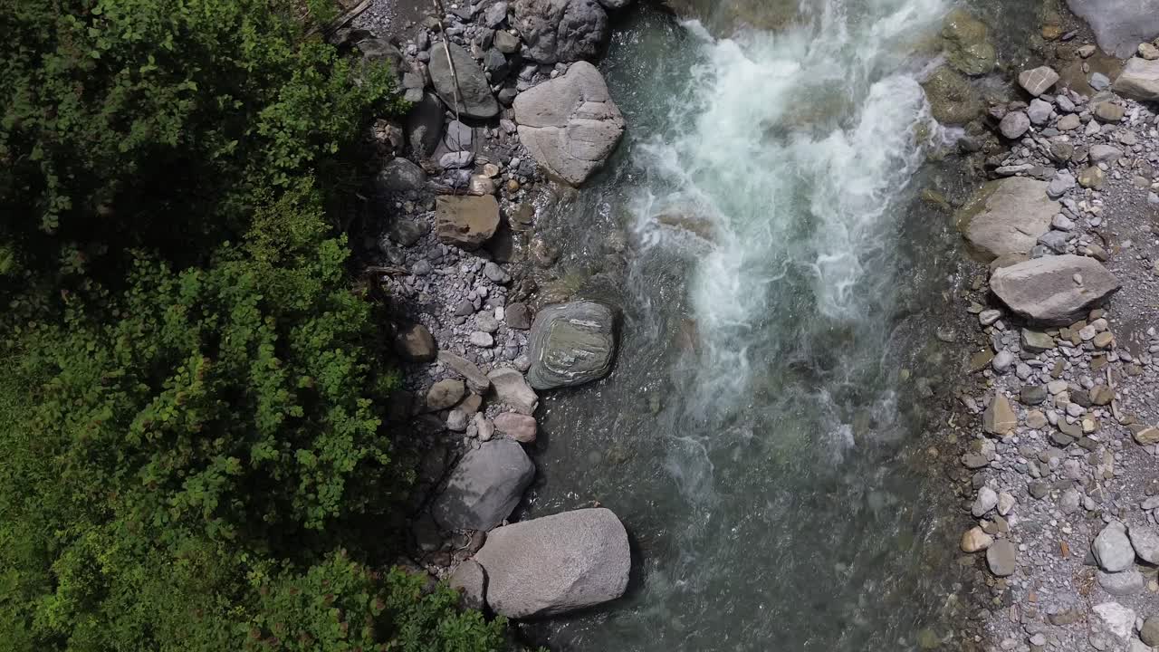Drone orbit above Turquoise Mountain River surrounded by Green Forest