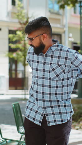 man with back pain sitting on a chair in the city