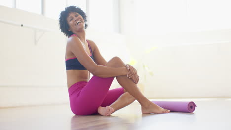 Biracial-yoga-instructor-sitting-on-floor,-laughing