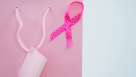 Animation-of-pink-present-bag-and-pink-ribbon-on-white-background