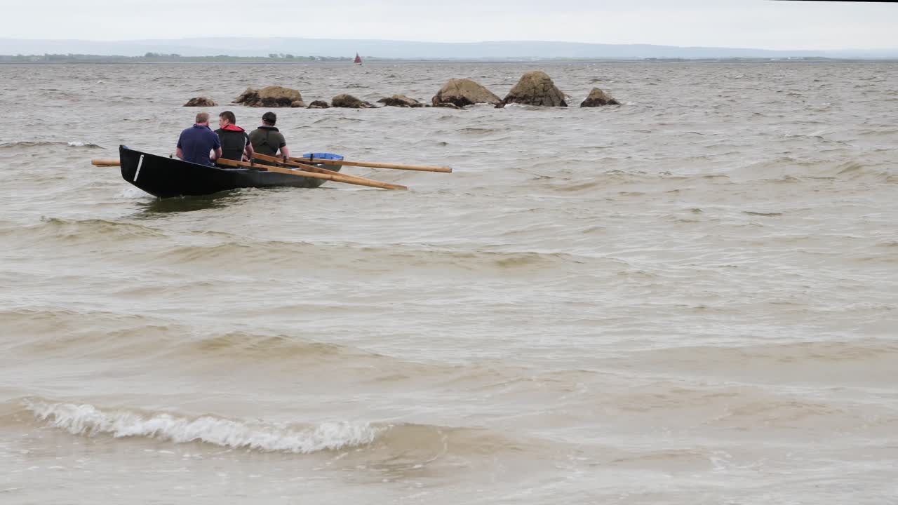 tripulación de tres remos y ser girado por las olas en el barco currach