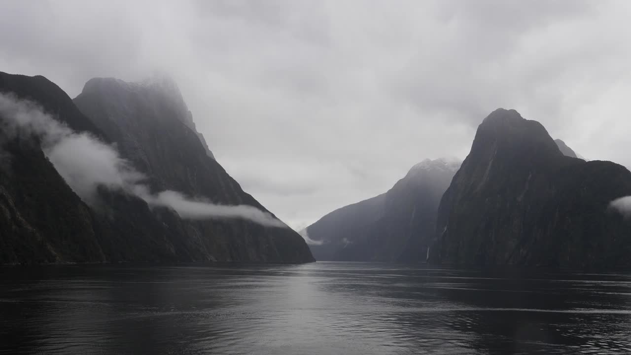 Out of this world landscape at Milford Sound (Piopiotahi), Fiordland National Park on the South Island of New Zealand. Milford Sound surrounded by looming mountains and impressive sheer rock faces.