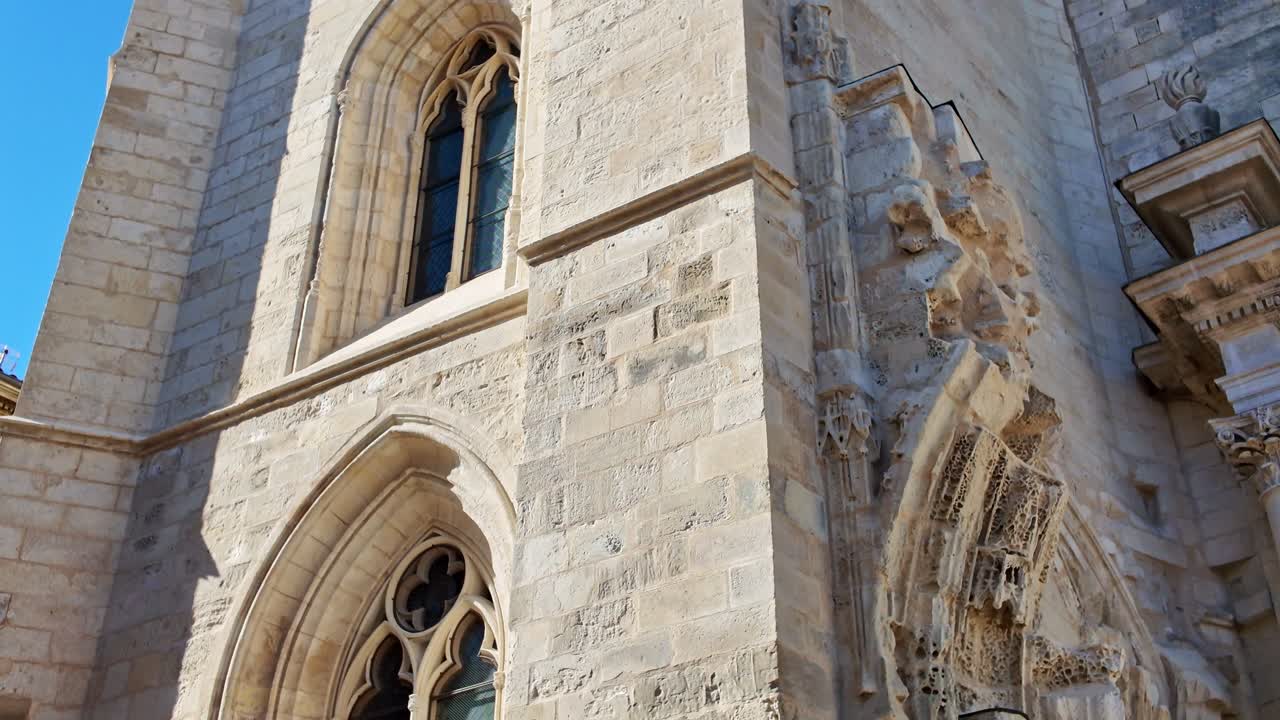 Low-angle view of historic Saint-Sauveur Church, detailed Gothic stone architecture, bell tower, arched windows, La Rochelle, France. Tilt-down