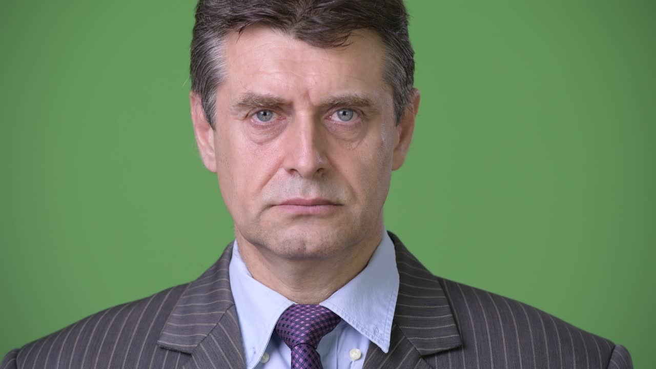 Mature handsome businessman against green background