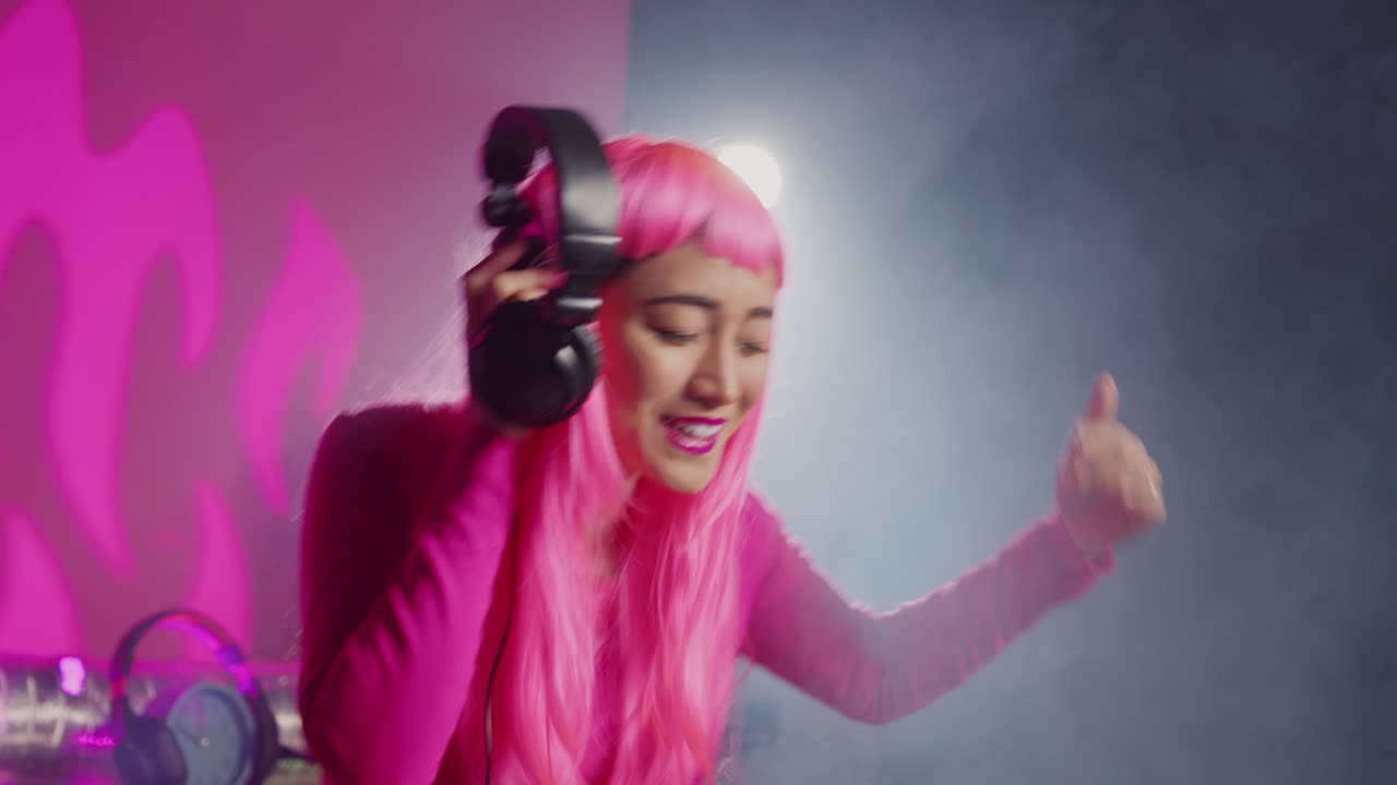 Woman with pink wig and headphones enjoying music