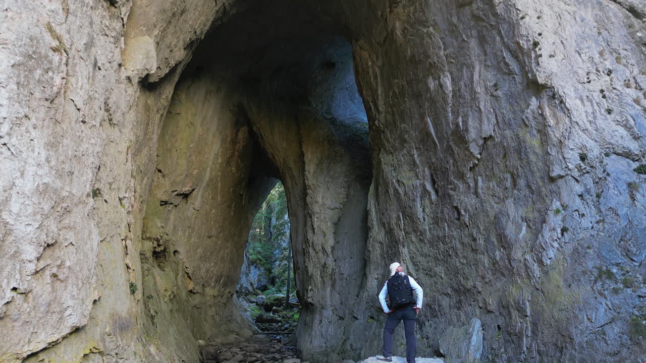 THE WONDERFUL BRIDGES: Seasoned senior hiker pausing near majestic double arch rock formation within rugged mountain canyon, enjoying serene wilderness landscape and geological marvel. Bulgaria