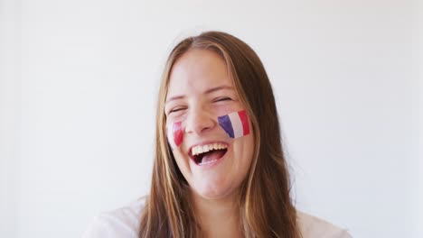 imagen de una mujer caucásica feliz con la bandera de francia aplaudiendo