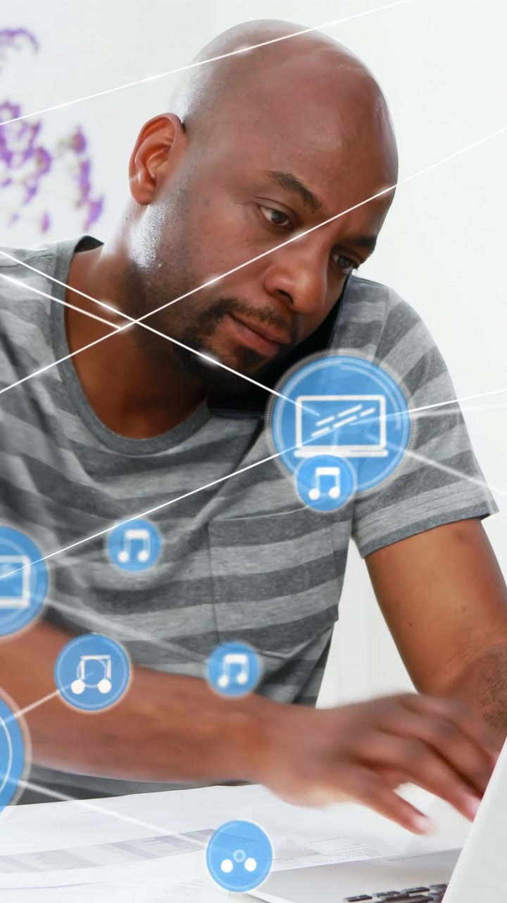 Vertical video: Man taking call, scanning docs and typing on laptop, blue HUD linking for business