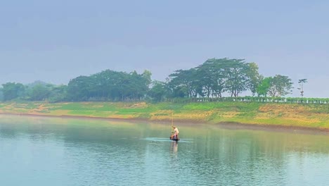 two people on board of traditional asian fishing boat crossing surma river, sylhet