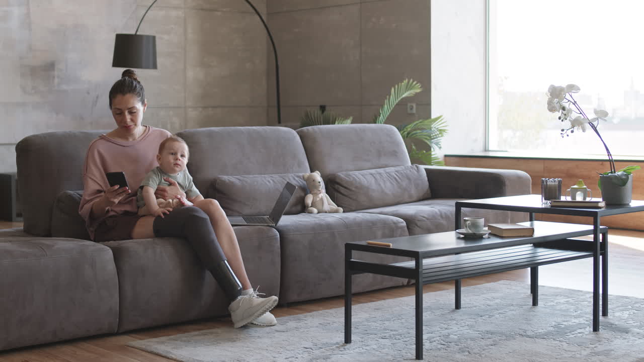 Woman with Disability Holding Toddler and Making Phone Call