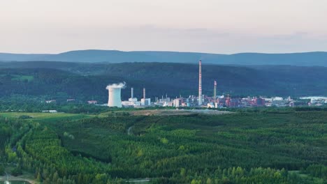 Aufschlussreiche-Drohnenaufnahme-Eines-Kohlekraftwerks-Und-Grüner-Landschaft,-Schornsteine-Und-Kühlturm