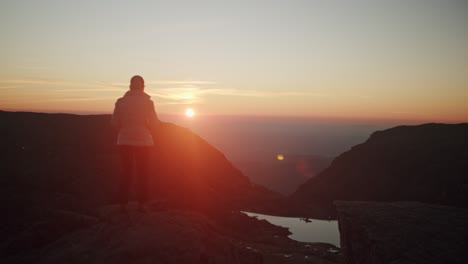 girl walks near a cliff in the mountains with epic sunset