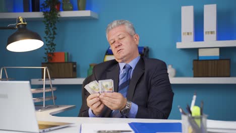the greedy businessman loves their money and kisses it.