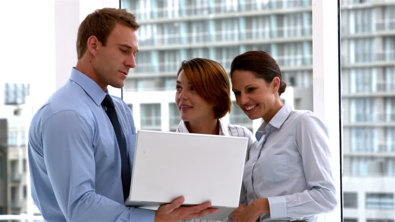 Gruppo di affari che sta insieme e che lavora al computer portatile
