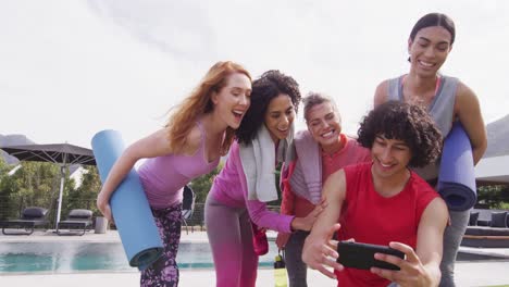 Fröhliche-Gruppe-Verschiedener-Freunde,-Die-Yogamatten-In-Der-Hand-Halten-Und-Ein-Selfie-Machen