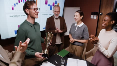 business team celebrating success with a trophy award in an office meeting
