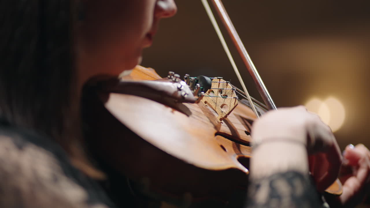여성의 손에 있는 오래된 바이올린의 클로즈업 여성 음악가는 바이올린을 연주하고 음악 홀에서 소나타를 연습하고 있습니다.